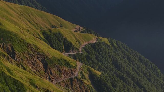 Aerial view of a winding road snaking across lush, green mountainsides offering a scenic passage through the Alazani pass, Chala, Tusheti, Georgia.