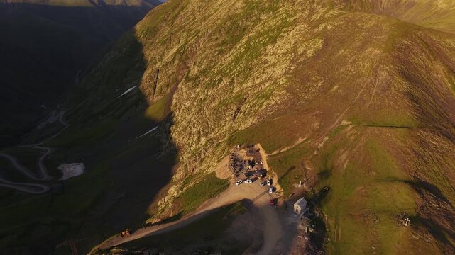 Aerial view of the Alazani pass, showing the rugged terrain and buildings nestled in the landscape, bathed in warm sunlight, Chala, Tusheti, Georgia.