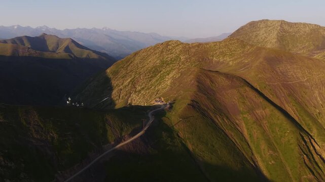 Aerial view of the Alazani pass reveals a stark contrast between sunlit slopes and shadowed valleys, highlighting the winding roads, Chala, Tusheti, Georgia.