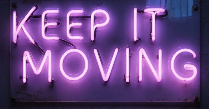 Bright pink neon sign displays text. Dark background emphasizes glowing message, Keep it moving. Simple, bold lettering creates strong visual impact.
