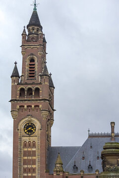 View of the Peace Palace's tower rises against the sky, its clock face a golden focal point, amidst the architectural grandeur, The Hague, South Holland, Netherlands.