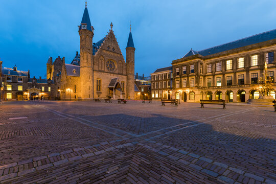 View of Gothic architecture and illuminated buildings frame a cobblestone square under a twilight sky, Binnenhof, the Hague, Netherlands.