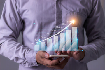 Young man with smartphone hand touching to visualize money growth The phone screen displays graphs and charts showing increasing investment and savings trends, along with an increased account balance