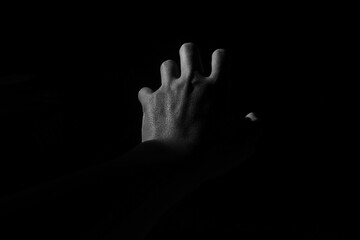 Fototapeta premium dramatic black and white of an open human palm reaching out from the darkness