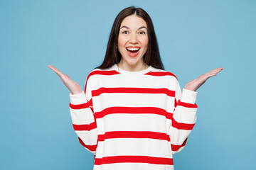 Young shocked surprised happy Caucasian woman she wear red striped sweatshirt casual clothes look camera spread hands isolated on plain pastel light blue background studio portrait. Lifestyle concept.