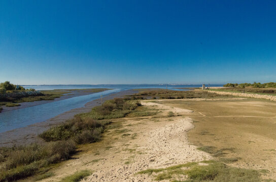 View of winding river flowing between sandy shores and grassy patches under a clear blue sky, a tranquil scene evoking a sense of peace, Arcachon, France.