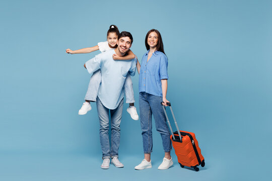 Traveler young fun parents mom dad child wear casual clothes hold suitcase bag isolated on plain blue background. Tourist travel abroad in free spare time rest getaway Air flight trip journey concept