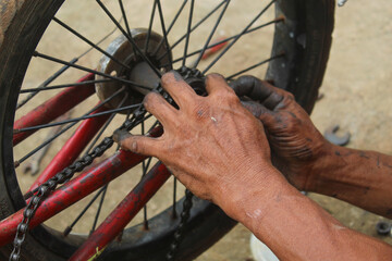 The mechanic's hands are dirty with oil and grease when repairing the bicycle axle.