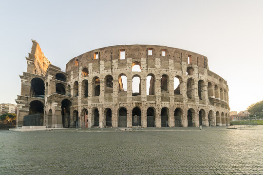 View of the ancient Colosseum, a testament to Roman history, standing majestically against the soft glow of dawn, its weathered stones whispering tales of gladiators and emperors, Rome, Lazio, Italy.