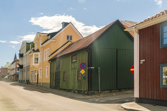 View of colourful wooden buildings line a quiet street under a bright sky, creating a charming tableau in Vastervik, Kalmar County, Sweden.