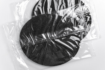 Circular filter element inside transparent pack on light background. Technical filtration component. Maintenance resource concept