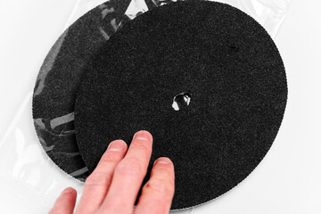 New black round water filter discs in transparent packaging touched by human hand. Replacement consumables