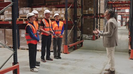 Warehouse manager instructing diverse team of workers - Powered by Adobe