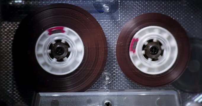 Close-up of transparent audio cassette. Audio Cassette Fast Rewind. Transparent compact cassette with brown tape rewinding at high speed.