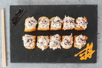 Deep-fried sushi rolls garnished with creamy crab salad and black sesame seeds.