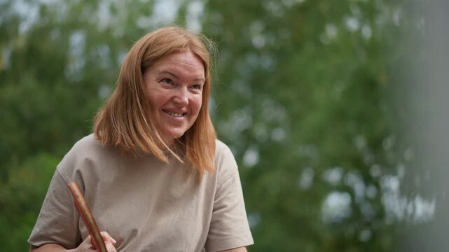 Woman Making Funny Faces Outside, Cheerful Woman In Outdoor Setting Performing Comedic Gestures, Vibrant Scene Of Woman With Paddle Exhibiting Humorous And Lively Expressions Outdoors