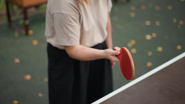 Woman With Paddle Ball, Woman Playing Paddle Ball On Table With Leaves Surrounding Her, Serene Woman Engages In Paddle Ball Training Outdoors Amidst Fallen Autumn Leaves And Green Scenery