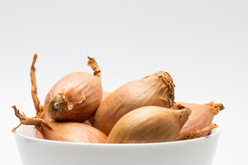 Chalotas frescas en cuenco blanco sobre fondo blanco