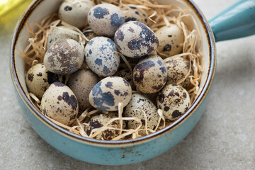 Turquoise serving bowl with raw fresh quail eggs, horizontal shot, close-up