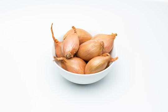 Chalotas frescas en cuenco blanco sobre fondo blanco