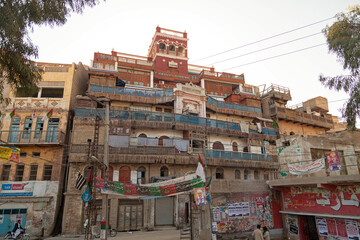 View of a multi-level building with faded colors and intricate balconies stands as a testament to time and culture, a captivating scene, Sukkur, Sindh, Pakistan.