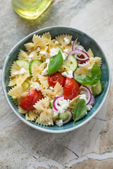 Bowl with italian farfalle pasta salad on a grey granite background, vertical shot, high angle view