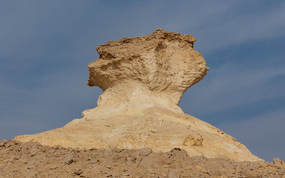 View of a weathered, tan, rock formation sculpted by the elements against a pale blue sky, a testament to nature's artistry, Zekreet, Al Sheehaniya Municipality, Qatar.