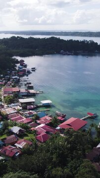 Vertical aerial panoramic establishing view of homes along Bastimentos Island&rsquo;s coastline in Bocas del Toro, Panama.