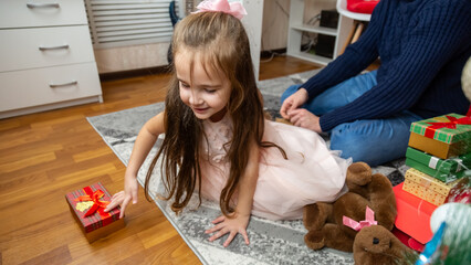 Happy father and daughter opening Christmas gifts together and smiling. Holidays concepts