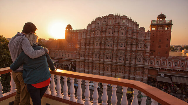 view of the couple gazing at the majestic Hawa Mahal against the warm hues of the setting sun, Jaipur, Rajasthan, India.