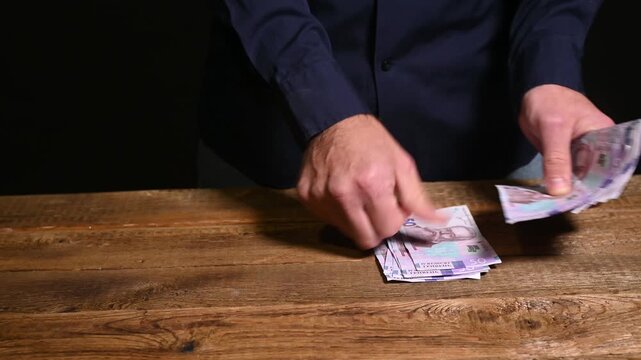 man carefully counts of fifty hryvnia banknotes, a close-up view of cash in hand. tangible process of handling and accounting paper money. accounting, business income and financial.