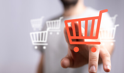 Close-up of a hand pointing to a shopping cart icon, representing online shopping, sales and...