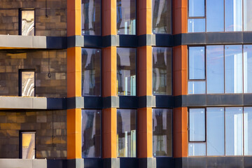 View of sunlight reflecting off the glass windows of a modern building with orange and dark gray panels, Aktau, Mangystau Region, Kazakhstan.