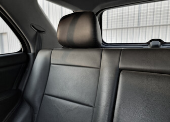 Rear seat in a car - view from front row. Wagon or SUV interior with sqaure-ish black leather seats with headrests.
