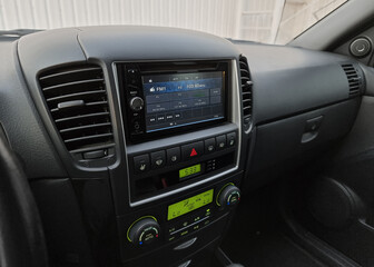 Close up shot of infotainment system in old car. Listening to radio while driving in a city in late afternoon.
