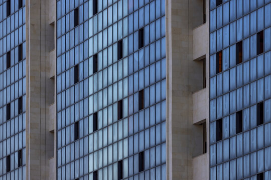 View of a modern building with repeating patterns of blue glass windows and concrete pillars reflecting the sky, creating an abstract urban landscape, Aktau, Mangystau Region, Kazakhstan.