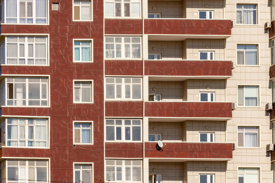 View of high-rise building featuring a striking contrast between the warm red facade and the cooler beige tones, creating a textured urban scene, Aktau, Mangystau Region, Kazakhstan.