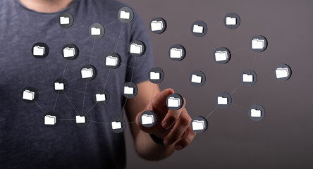 Conceptual image of a man interacting with a network of digital data folders on a futuristic interface. Highlig