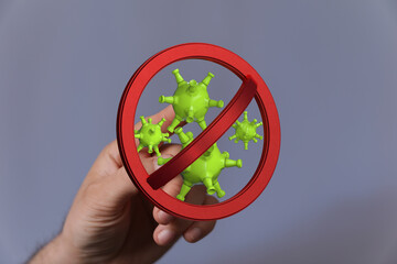 Symbol of virus control and protection. Hand holds sign with viruses crossed out. Concept of prevention and se