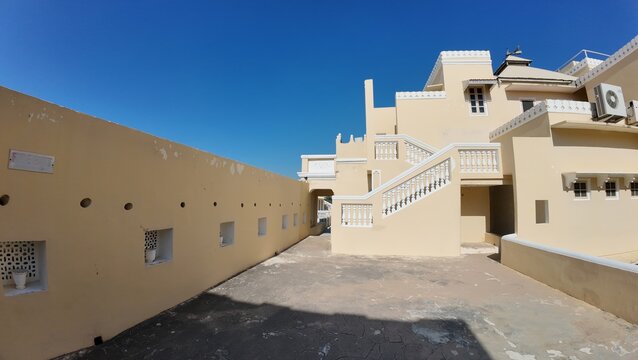 Exterior View of the Historic Mandawa Fort Rooftop Featuring Heritage Architecture and Vibrant Yellow Walls under a Clear Blue Sky
