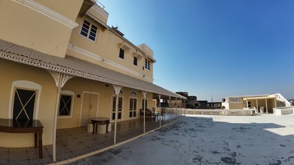 Exterior View of the Historic Mandawa Fort Rooftop Featuring Heritage Architecture and Vibrant Yellow Walls under a Clear Blue Sky