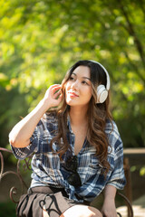 A beautiful Asian teenage girl is happily listening to music with headphones.