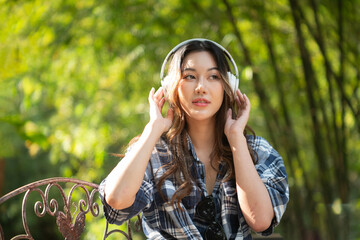A beautiful Asian teenage girl is happily listening to music with headphones.