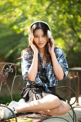 A beautiful Asian teenage girl is happily listening to music with headphones.