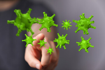 Hand pointing towards green coronavirus cells, symbolizing pandemic threat and infection risk. Representing co