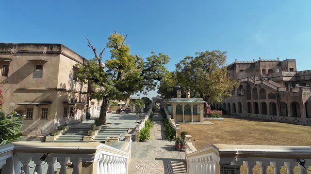 Scenic View of a Sunlit Heritage Courtyard at Mandawa Fort in Rajasthan Featuring Traditional Stone Gazebos and Lush Green Plants