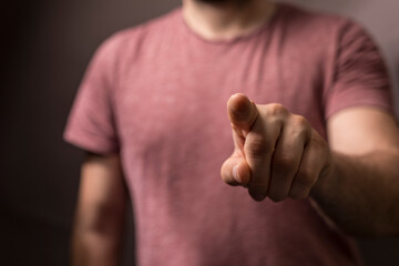 Close-up of a man's hand pointing directly at the camera. Represents choice, decision, direction, and accusation