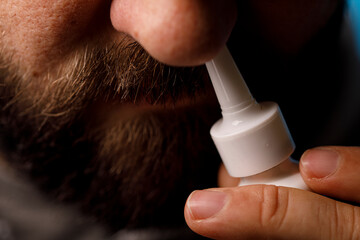 Close-up of a man using a nasal spray.  Concept of sickness, flu, allergies. Healthcare and medicine concept.
