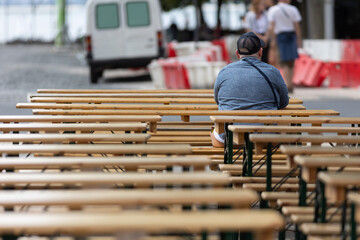 Person sitting alone on wooden bench during outdoor event