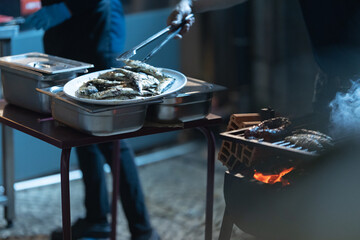 Person serving fresh grilled fish at outdoor barbecue